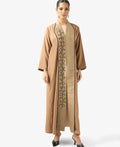 Woman wearing a beige abaya with intricate embroidery on a white background