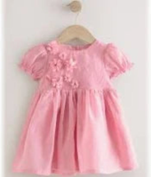 Pink dress with floral details on a hanger against a white background